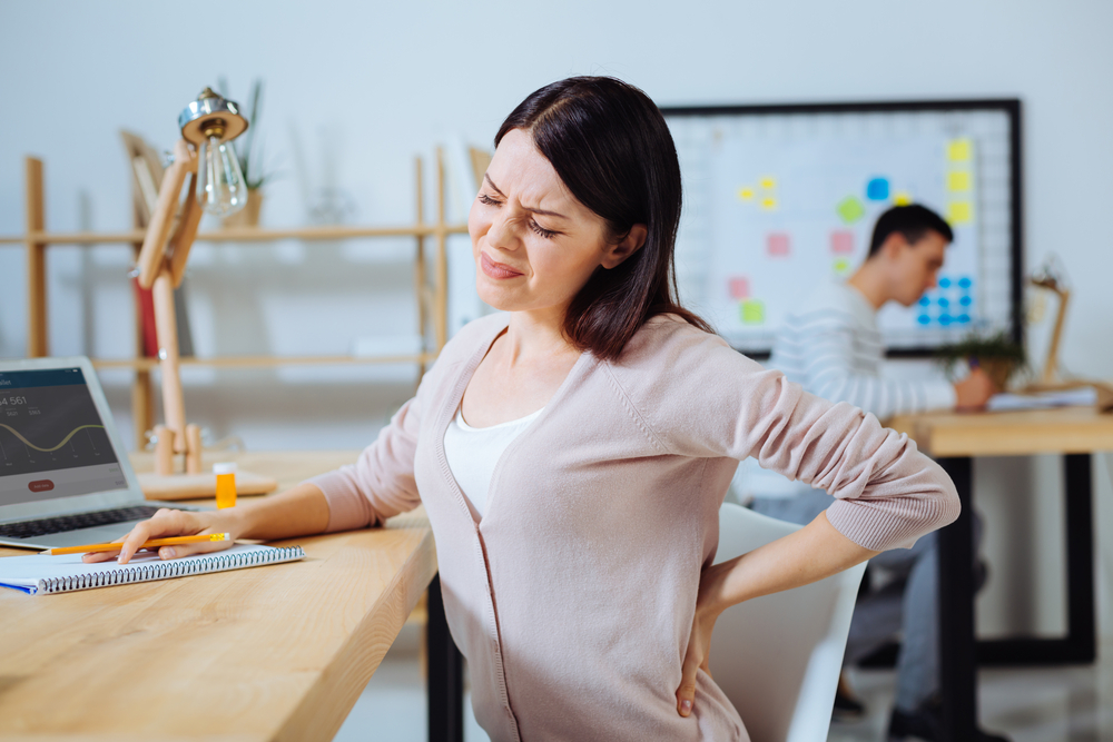 Women sitting at a table holding back in pain