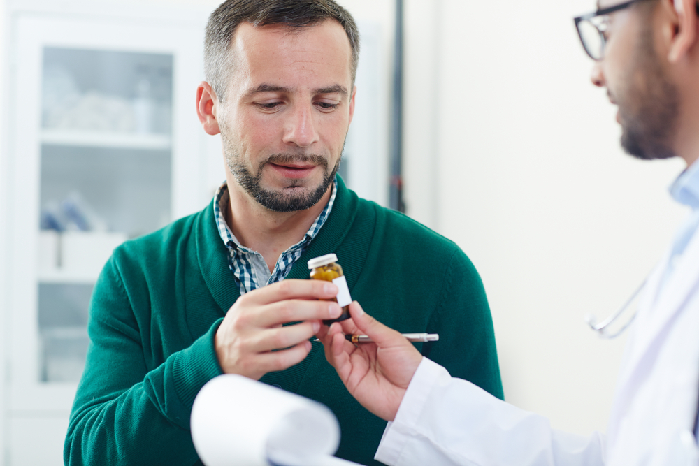 Sick patient taking pill-bottle with medication or vitamins from doctor hands