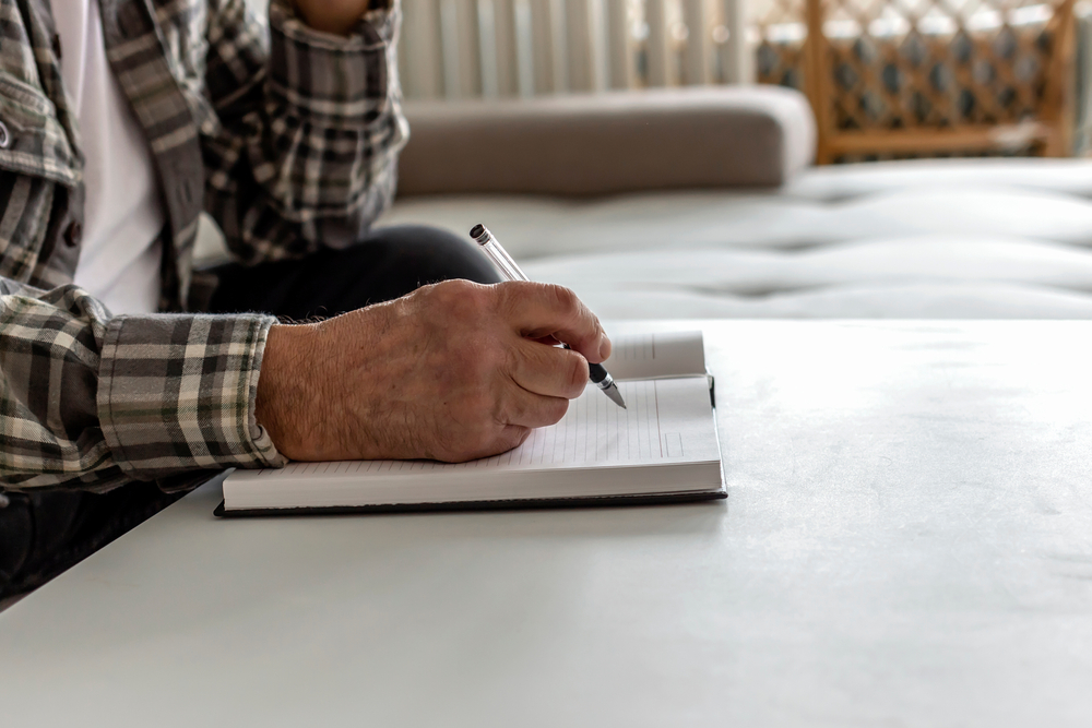 older man writing something down on a diary with pen